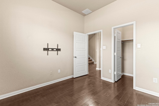 unfurnished bedroom with dark hardwood / wood-style floors, a walk in closet, and a closet