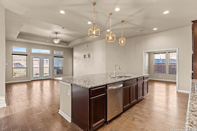 kitchen with pendant lighting, sink, stainless steel dishwasher, light hardwood / wood-style floors, and light stone counters