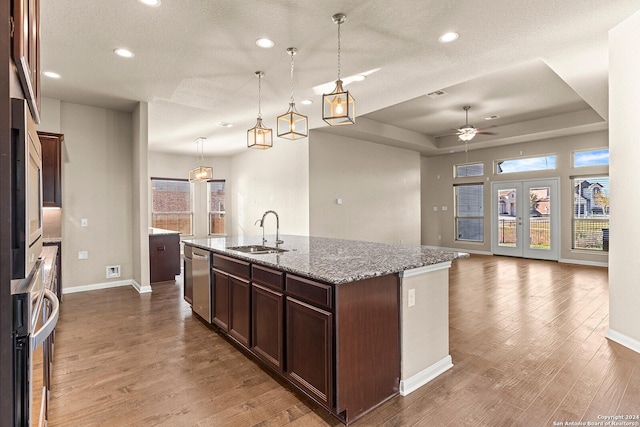 kitchen with a kitchen island with sink, sink, hardwood / wood-style floors, and light stone counters