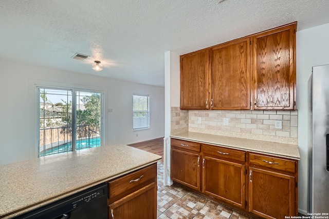 kitchen with tasteful backsplash, light stone countertops, dishwasher, and a textured ceiling