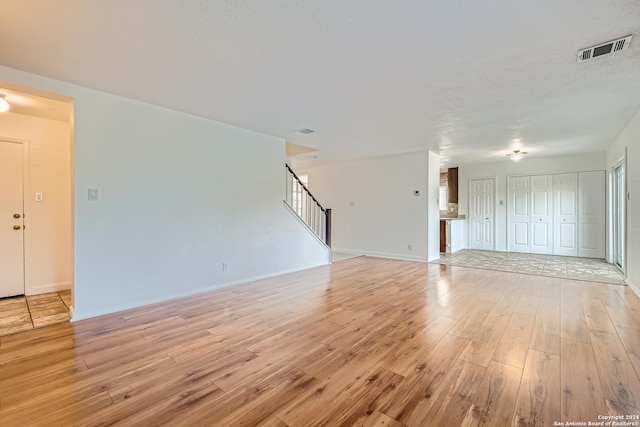 unfurnished living room featuring a textured ceiling and light wood-type flooring