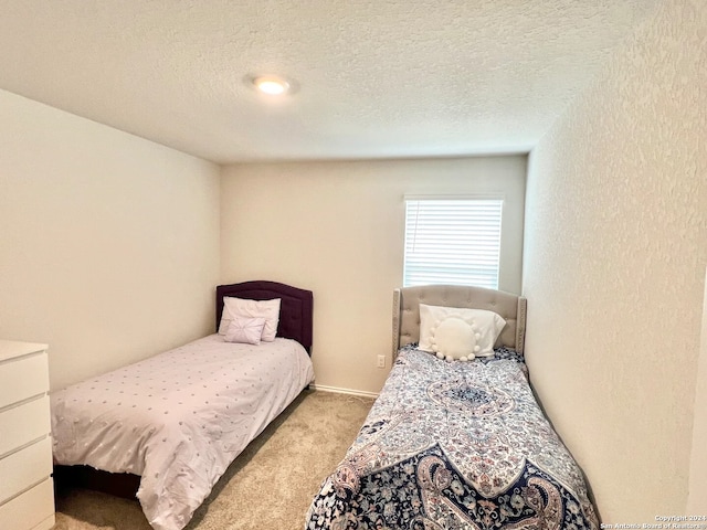 bedroom featuring a textured ceiling and light colored carpet