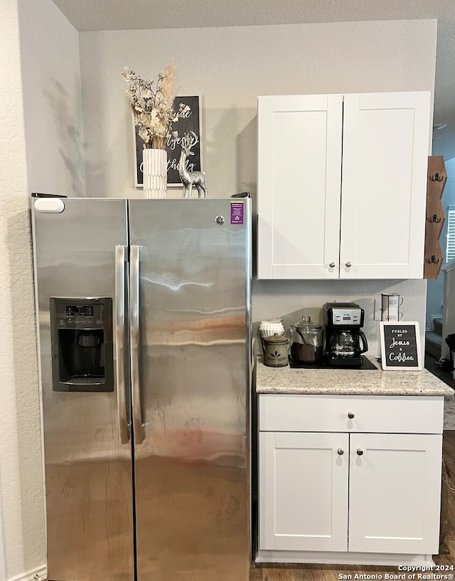 kitchen with white cabinetry, light stone counters, and stainless steel refrigerator with ice dispenser