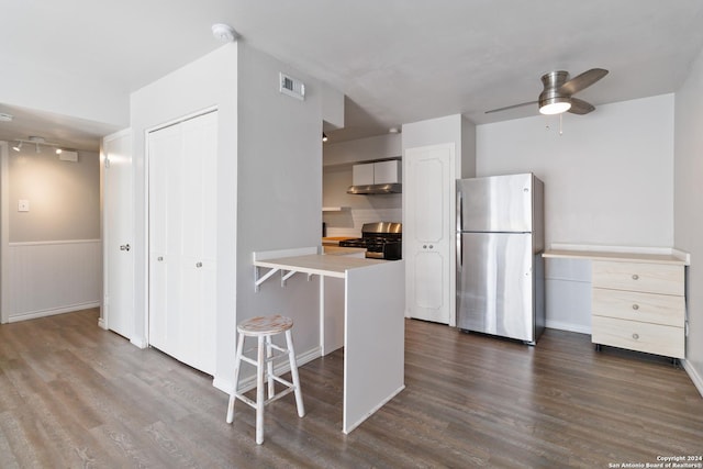 8038 Broadway Unit 225L, San Antonio, TX 78209 - kitchen featuring dark wood-style flooring, visible vents, appliances with stainless steel finishes, wall chimney range hood, and a kitchen breakfast bar