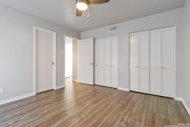 8038 Broadway Unit 225L, San Antonio, TX 78209 - unfurnished bedroom featuring baseboards, visible vents, ceiling fan, wood finished floors, and two closets