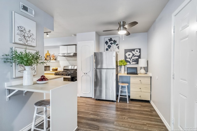 8038 Broadway Unit 225L, San Antonio, TX 78209 - kitchen featuring appliances with stainless steel finishes, wall chimney exhaust hood, a kitchen bar, white cabinets, and dark wood-style flooring
