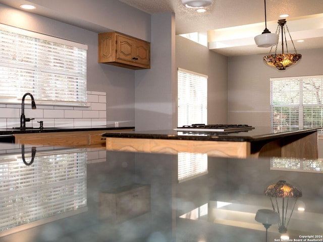 kitchen with decorative backsplash, a wealth of natural light, and decorative light fixtures