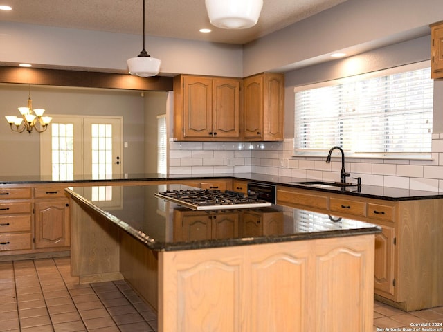 kitchen with sink, stainless steel gas cooktop, dark stone counters, decorative backsplash, and light tile patterned floors