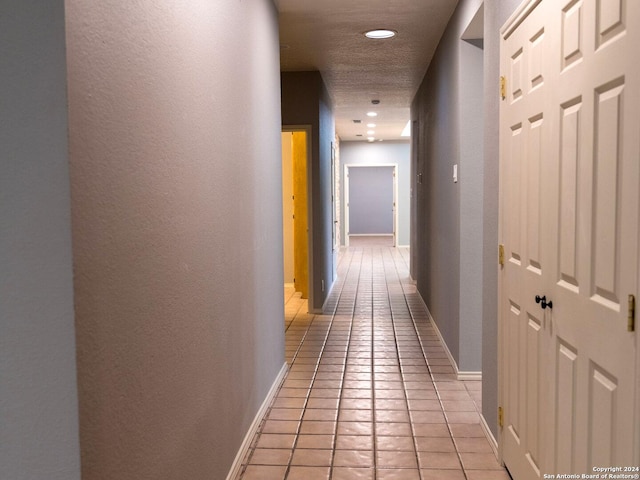 corridor featuring light tile patterned floors and a textured ceiling