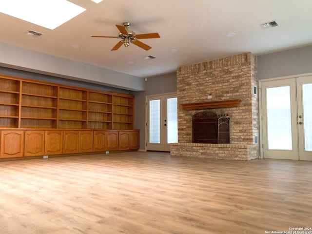 unfurnished living room with french doors, light hardwood / wood-style flooring, and a brick fireplace