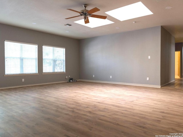 empty room featuring hardwood / wood-style flooring, a skylight, and ceiling fan