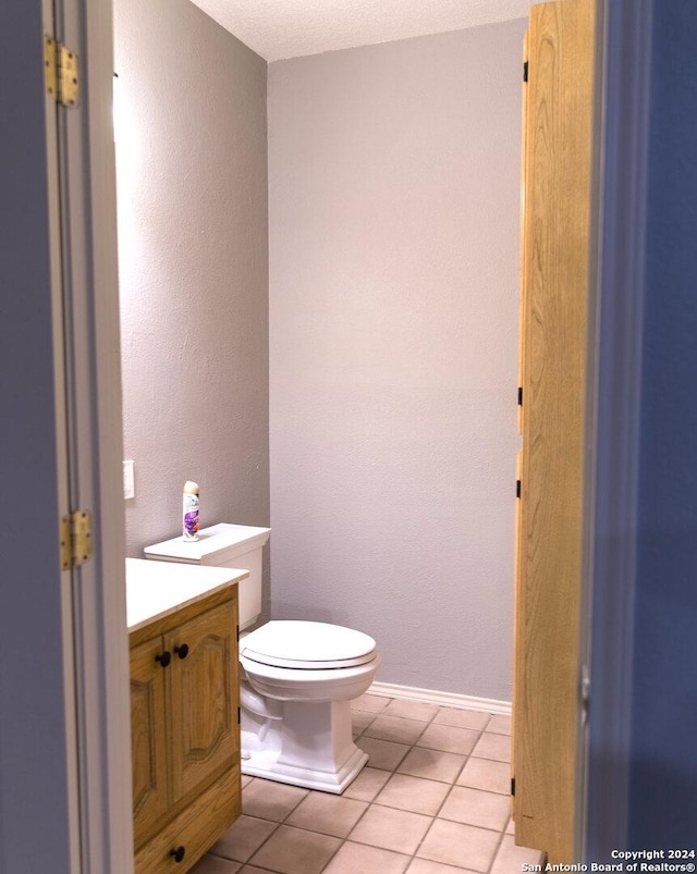 bathroom with toilet, a textured ceiling, vanity, and tile patterned floors