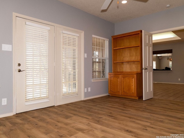 interior space with ceiling fan, wood-type flooring, and a textured ceiling