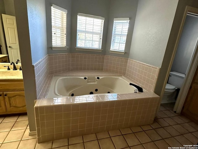 bathroom featuring tile patterned floors, vanity, toilet, and tiled bath