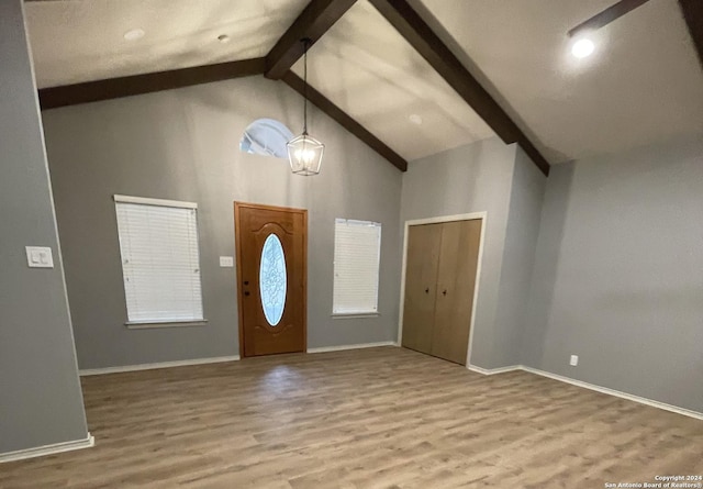 entrance foyer featuring beamed ceiling, light wood-type flooring, an inviting chandelier, and high vaulted ceiling