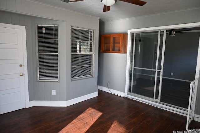 spare room with ceiling fan, crown molding, and dark wood-type flooring