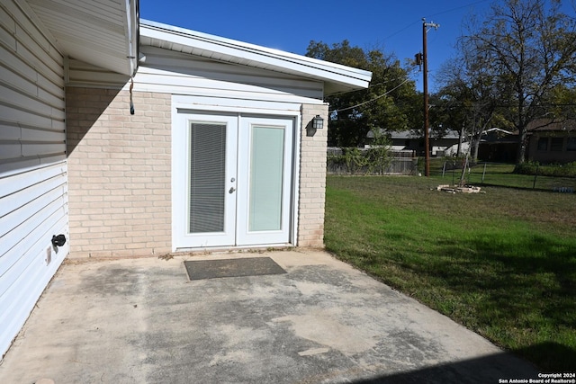 view of exterior entry featuring a yard, french doors, and a patio