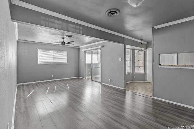 empty room featuring hardwood / wood-style flooring, plenty of natural light, ceiling fan, and crown molding