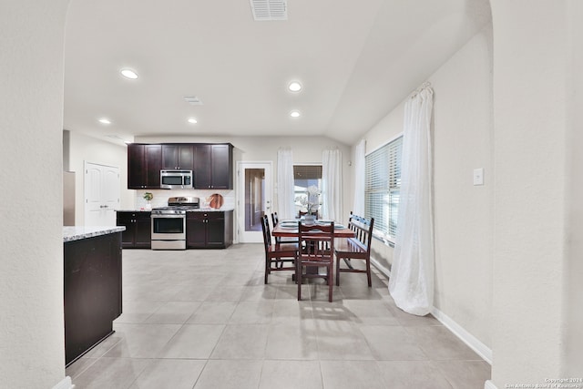 tiled dining area featuring vaulted ceiling