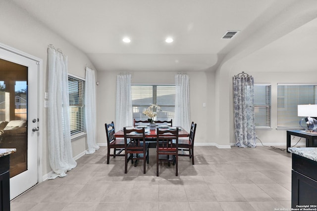 dining space featuring light tile patterned floors and vaulted ceiling