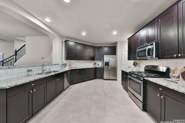 kitchen featuring dark brown cabinetry, stainless steel appliances, backsplash, and sink