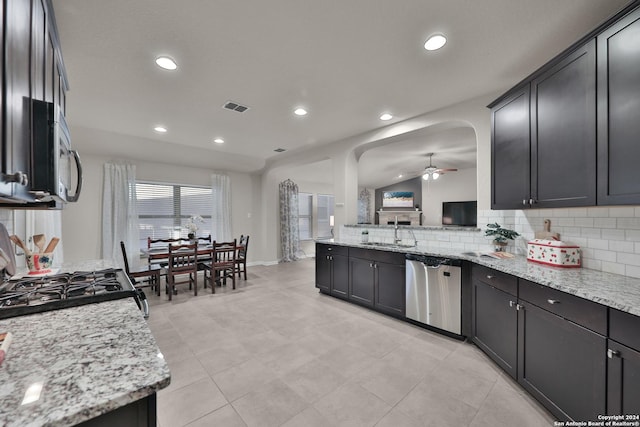 kitchen featuring light stone countertops, stainless steel appliances, vaulted ceiling, ceiling fan, and sink