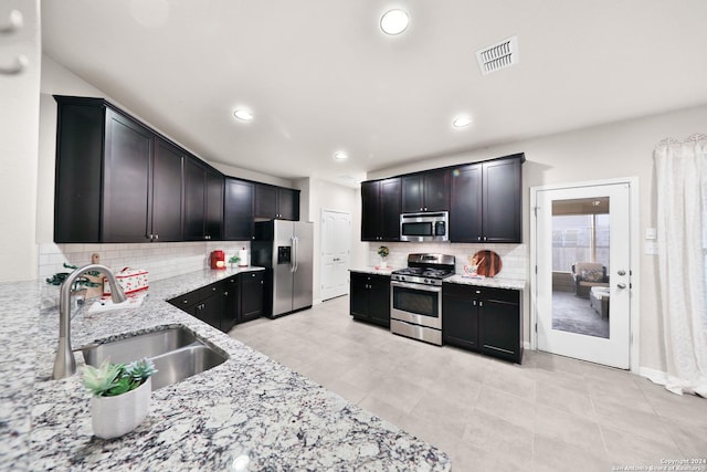 kitchen featuring light stone counters, sink, appliances with stainless steel finishes, and tasteful backsplash