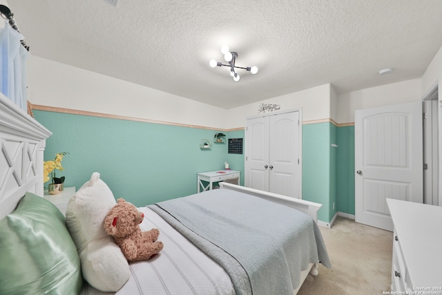 carpeted bedroom featuring a notable chandelier, a textured ceiling, and a closet