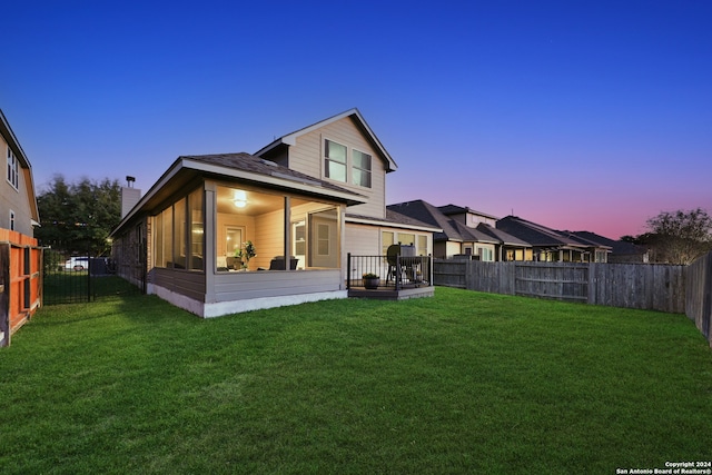 back house at dusk featuring a yard and a wooden deck