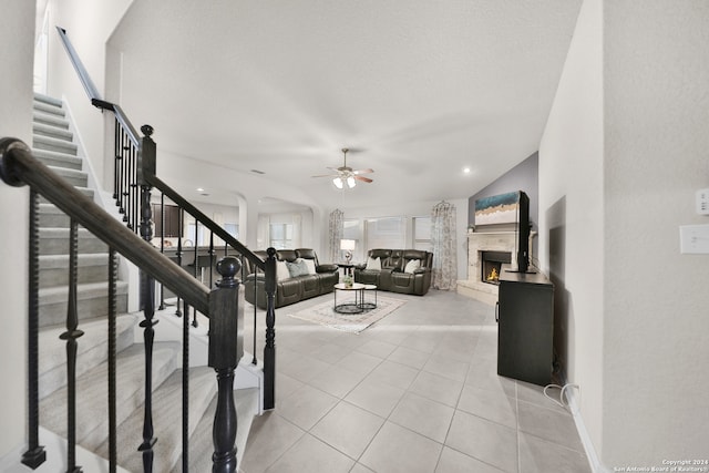 living room featuring a textured ceiling, ceiling fan, light tile patterned floors, a premium fireplace, and lofted ceiling