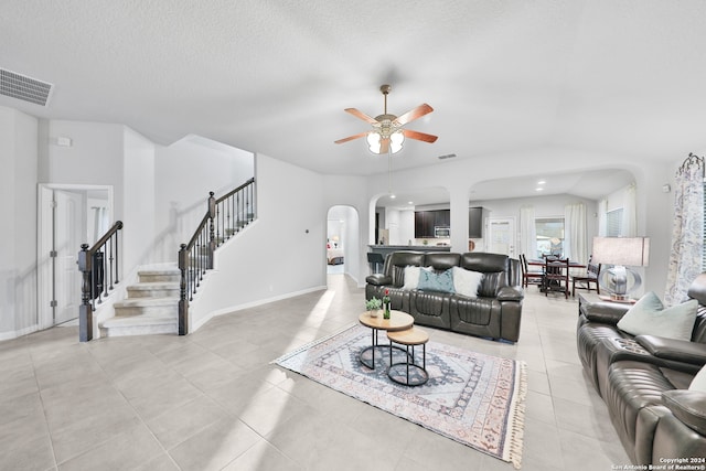 tiled living room with ceiling fan and a textured ceiling