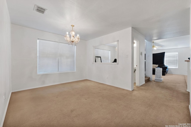 empty room with ceiling fan with notable chandelier and light colored carpet