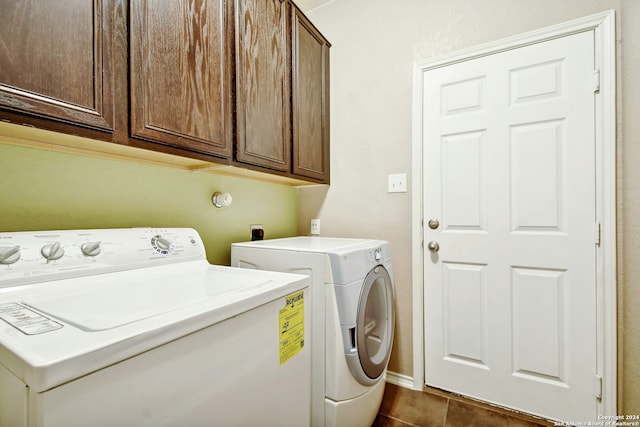 laundry room with washer and dryer, cabinets, and dark tile patterned flooring