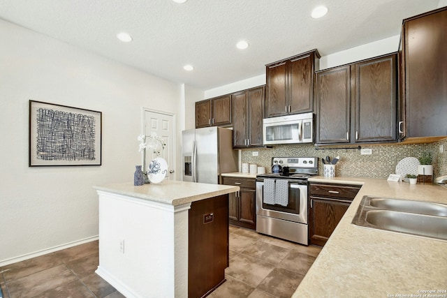 kitchen featuring appliances with stainless steel finishes, backsplash, dark brown cabinetry, and sink