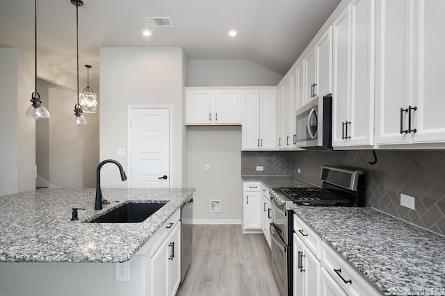 kitchen with sink, white cabinetry, stainless steel appliances, and a kitchen island with sink