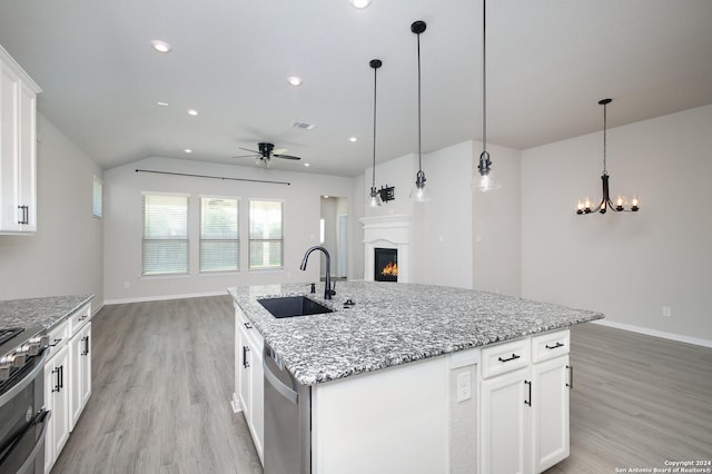 kitchen featuring white cabinets, ceiling fan with notable chandelier, dishwasher, and an island with sink