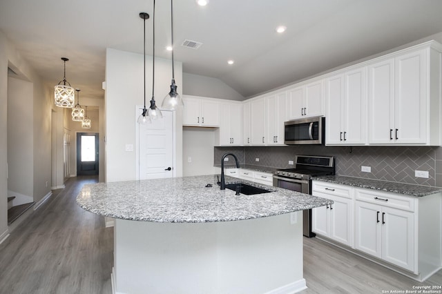 kitchen with a kitchen island with sink, white cabinets, sink, decorative backsplash, and appliances with stainless steel finishes