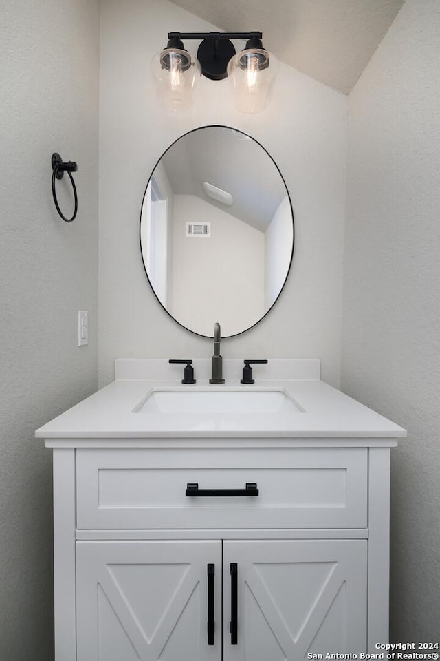 bathroom with vanity and lofted ceiling