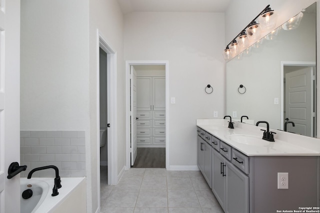 bathroom with tile patterned flooring, vanity, a tub to relax in, and toilet