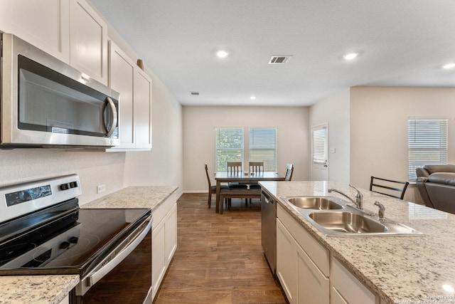 kitchen featuring sink, light stone countertops, appliances with stainless steel finishes, dark hardwood / wood-style flooring, and white cabinetry