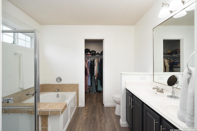 bathroom featuring hardwood / wood-style flooring, vanity, toilet, and a tub