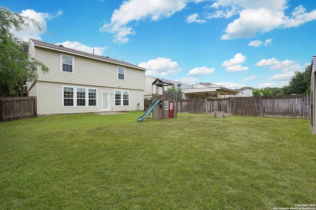 back of property with a playground and a yard