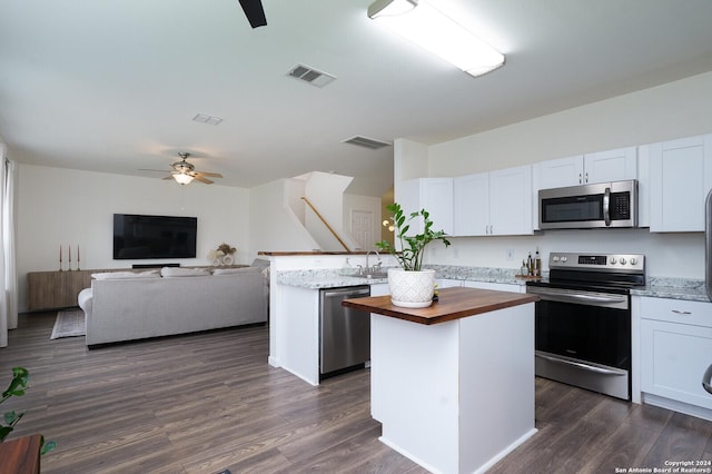 kitchen with a center island, dark hardwood / wood-style flooring, butcher block countertops, white cabinets, and appliances with stainless steel finishes