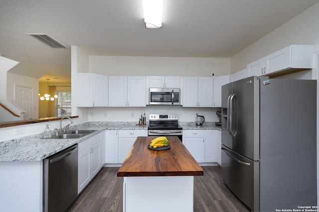 kitchen with sink, a center island, dark wood-type flooring, stainless steel appliances, and butcher block countertops