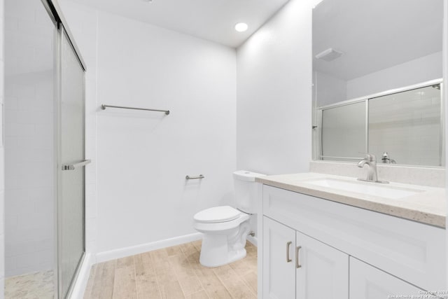 bathroom with wood-type flooring, vanity, toilet, and a shower with shower door