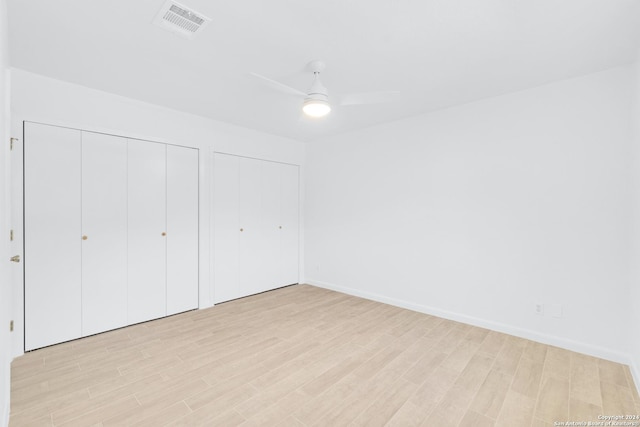 unfurnished bedroom with ceiling fan, two closets, and light hardwood / wood-style flooring