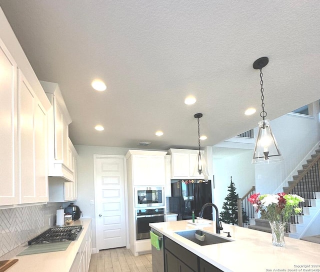 kitchen featuring white cabinets, sink, appliances with stainless steel finishes, tasteful backsplash, and decorative light fixtures