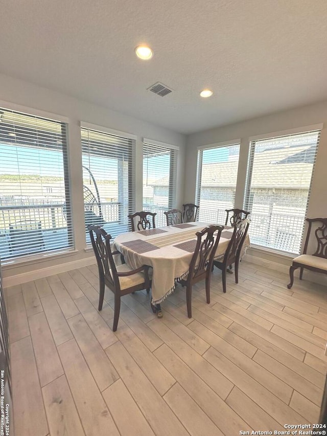 dining space featuring a textured ceiling, light hardwood / wood-style floors, and a wealth of natural light