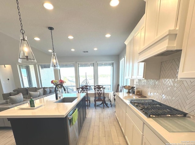 kitchen featuring a center island with sink, sink, light hardwood / wood-style flooring, decorative light fixtures, and white cabinetry