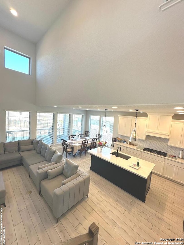 living room featuring a high ceiling, light hardwood / wood-style floors, and sink